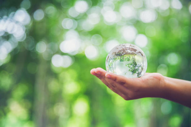 istock Human hands holding earth sphere crystal or sustainable globe glass with sunlight at green nature background in ecology environment forest. concept of conservation environmental, protection planet. 1420716526