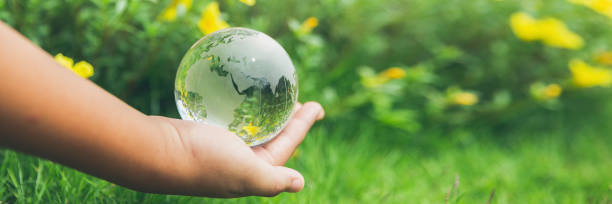 istock Human hands holding earth sphere crystal or sustainable globe glass with sunlight at green nature background in ecology environment forest. concept of conservation environmental, protection planet. 1420716924