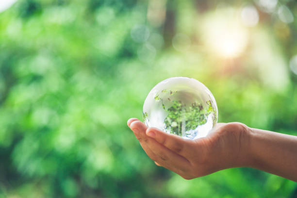 istock Human hands holding earth sphere crystal or sustainable globe glass with sunlight at green nature background in ecology environment forest. concept of conservation environmental, protection planet. 1420716963