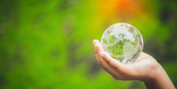 istock Human hands holding earth sphere crystal or sustainable globe glass with sunlight at green nature background in ecology environment forest. concept of conservation environmental, protection planet. 1420717024