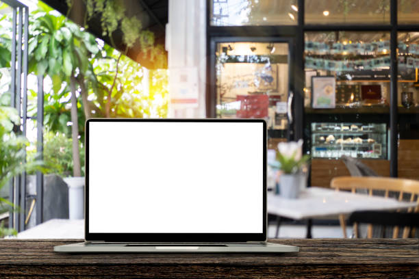 istock Blank screen laptop computer on wood table top with blur cafe restaurant with abstract bokeh light defocused 1420717031