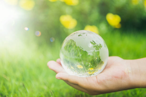 istock Human hands holding earth sphere crystal or sustainable globe glass with sunlight at green nature background in ecology environment forest. concept of conservation environmental, protection planet. 1420717089