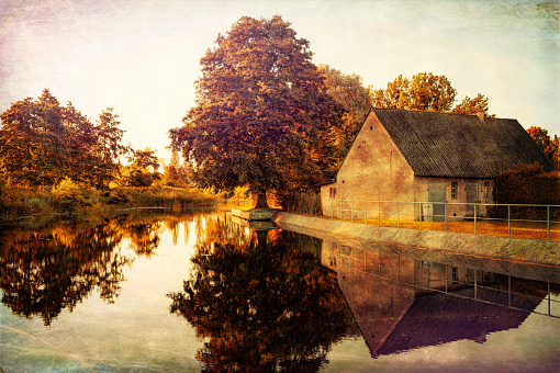 Beautiful peaceful autumn countryside. Old abandoned village barn and trees reflected in the lake. Indian summer sunset