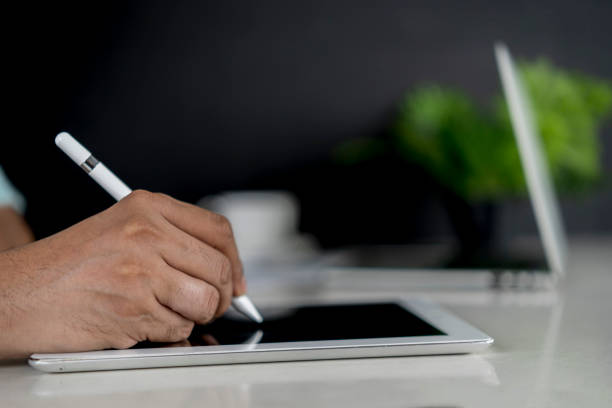 istock Closeup hand signing or using digital pen on computer tablet on the desk 1420724434