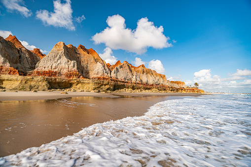 This is a stony/rocky beach near Seaford with chalk hills and grassy hills and a stony beach. There are paths, waves fences, clouds, rocks and blue sky's.