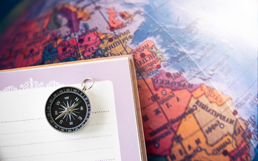 a compass placed on a notebook on the map background travel geographic navigation concept background
