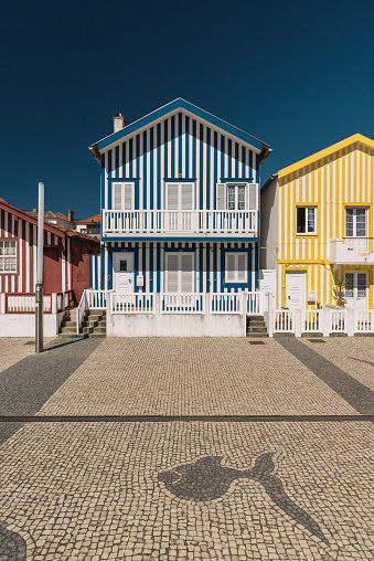 Costa Nova village, Aveiro, Portugal - July 07, 2022: The image represents the historical fisherman's houses with colorful striped facade. It is famouse touristic place in Portugal. People come here not only for big beaches but also to see these buildings.