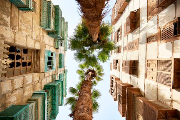 Vernacular architecture and palm trees in Al-Balad, Jeddah View from directly below traditional residential buildings featuring balconies and mashrabiya woodwork in historic district under restoration. islamic architecture stock pictures, royalty-free photos & images