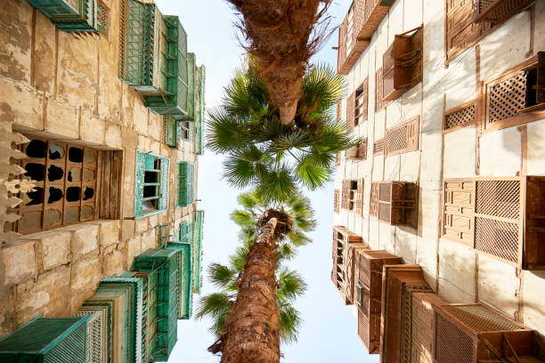 Vernacular architecture and palm trees in Al-Balad, Jeddah View from directly below traditional residential buildings featuring balconies and mashrabiya woodwork in historic district under restoration. jeddah stock pictures, royalty-free photos & images