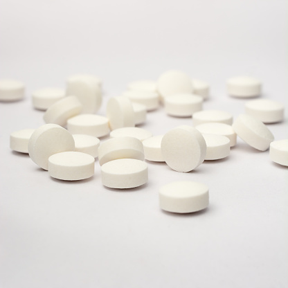 white round pills or tablets scattered on white background, medical drugs taken soft-focus with copy space