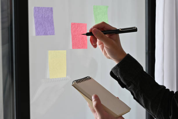 istock Cropped view portrait of a man taking note on a sticky note while holding a note pad. For business and finance concept. 1420729731