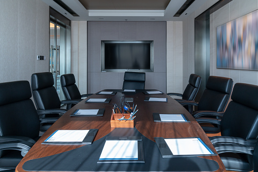 A huge meeting room with bright Windows and two rows of comfortable chairs, large conference tables, projection equipment, and elegant red carpets and so on.