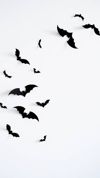 istock Closeup black paper bats on white wall,copy space,decor for holiday.Interior decoration concept for happy halloween,day of the dead celebration.Top view,flat lay. Holiday postcard 1420731239