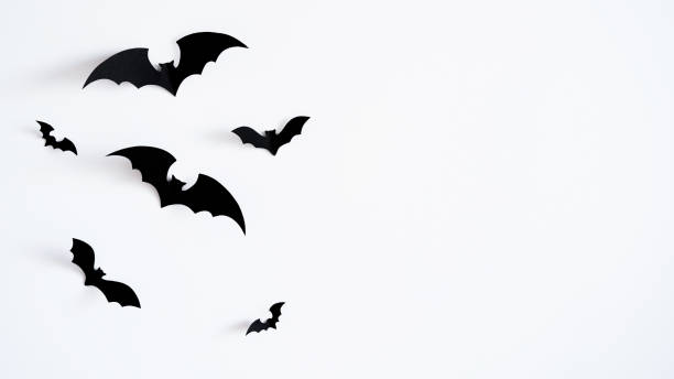 istock Closeup black paper bats on white wall,copy space,decor for holiday.Interior decoration concept for happy halloween,day of the dead celebration.Top view,flat lay. Holiday postcard 1420731242