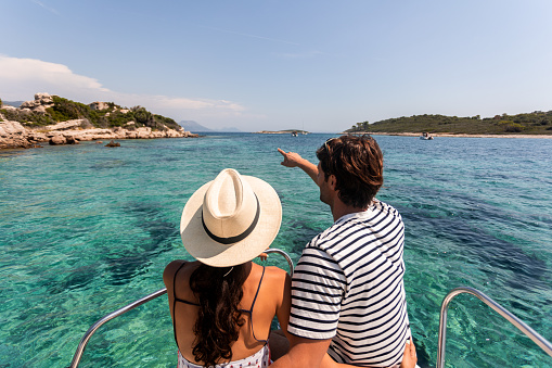 Rear view of small group of friends in bikini sitting on boat and admiring sea view