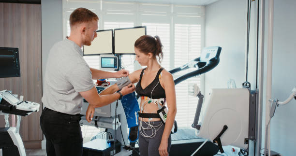 fitness, tecnologia e mulher com tecnologia de saúde testando pressão arterial para verificação da frequência cardíaca ou monitore a respiração. mulher atlética em teste de protótipo para exercício, bem-estar e treinamento em uma clínica. - clínica de treino desportivo - fotografias e filmes do acervo