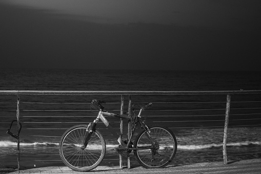 Alone forgotten bike near the seaside, black and white photo of a bicycle at the beach, concept of loneliness