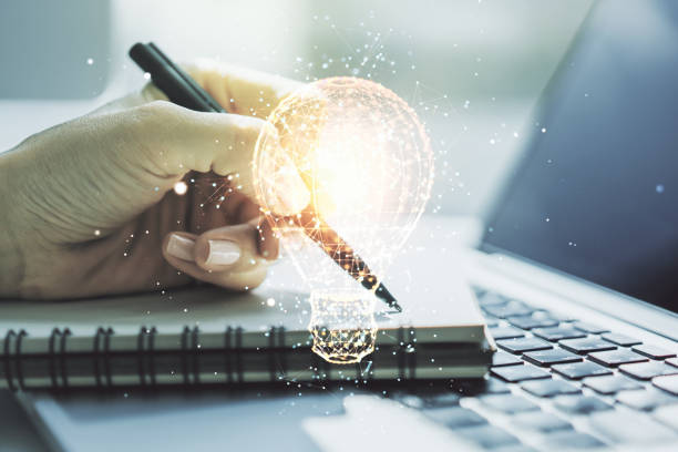 istock Creative idea concept with light bulb illustration and hand writing in notebook on background with laptop. Multiexposure 1420741188