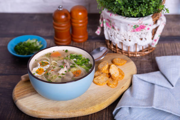 Soup with chicken, noodles, potatoes, quail eggs and carrots. Seasoned with onions and parsley. Close-up, selective focus