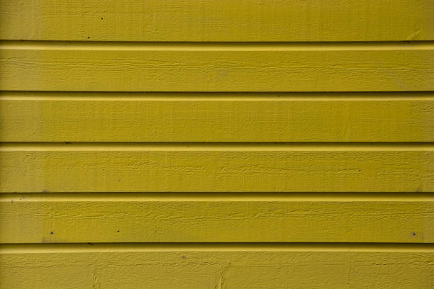 close up of yellow painted wood siding on an exterior wall background