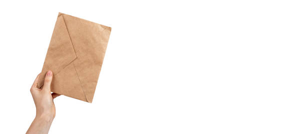 istock Banner with hand holding kraft paper envelope isolated on white background. Eco-friendly package for letter, invitation, postcard. Copy space 1420750833