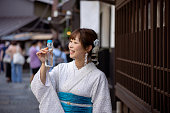 日本の伝統的な商店街で「ラムネ」ソーダポップを飲む白い夏の着物を着た女性