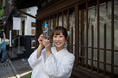日本の伝統的な商店街で「ラムネ」ソーダポップを手にした白い夏の着物を着た女性