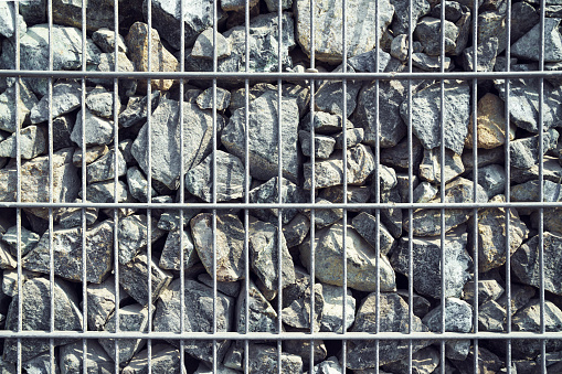 Wire Gabion Rock Fence. Metal Cage filled with rocks. Nicely lit useful backgroud. Texture background of rock fence with cage