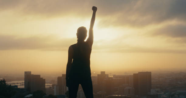 siluetta di donna per la leadership, il successo e la libertà sul tramonto della montagna con la celebrazione prima per il potere. orgoglioso vincitore come ispirazione per il successo, forte motivazione e responsabilizzazione del leader - women standing fist success foto e immagini stock