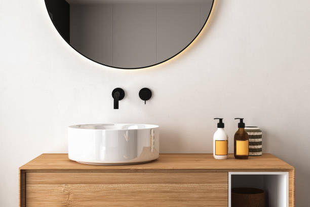 istock Close up of sink with oval mirror standing in on white wall 1420766207