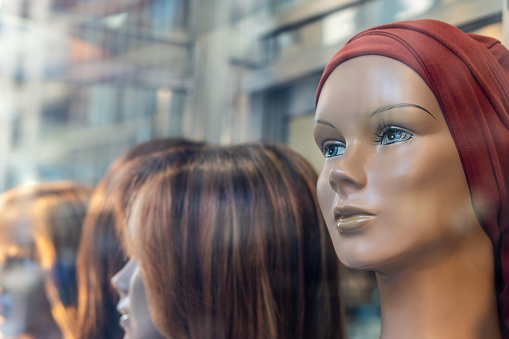 Female mannequin heads with wigs, behind a wig shop window