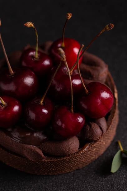 istock Cake with cherry and chocolate cream on a black plate 1420770202
