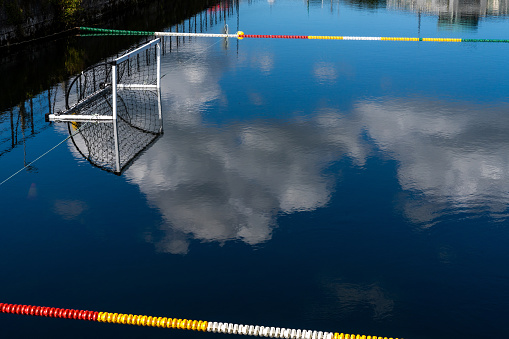A water polo field with floats and empty goal in calm water with reflections of sky