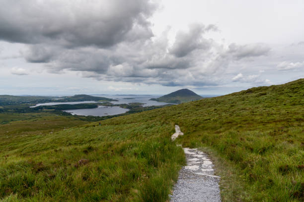 hiking trail descending from Diamond Hill mountain peak in Connemara National Park with a view of the coast and Kingstown Peninusla the hiking trail descending from Diamond Hill mountain peak in Connemara National Park with a view of the coast and Kingstown Peninusla connemara national park stock pictures, royalty-free photos & images