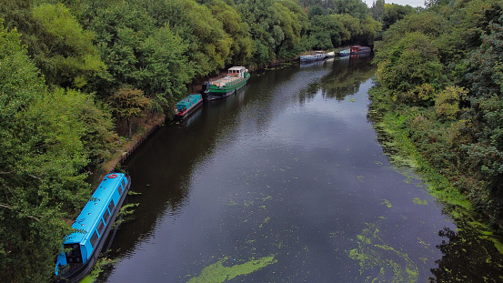 Drone point of view of canal boats moored amongst trees