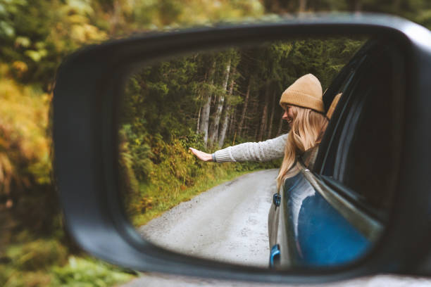 Road trip vacations woman tourist traveling by rental car active lifestyle outdoor in Norway autumn forest view mirror reflection stock photo
