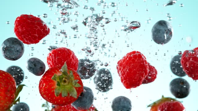 Super slow motion of falling berries into water.