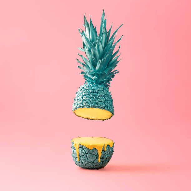 istock Bright, creative concept of fruit and summer on a pink background. Blue sliced pineapple bleeds yellow paint. 1420788363