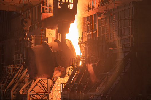 Casting ladle in oxygen converter process area. Workshop at big steel mill. Hot pig iron pouring into oven.