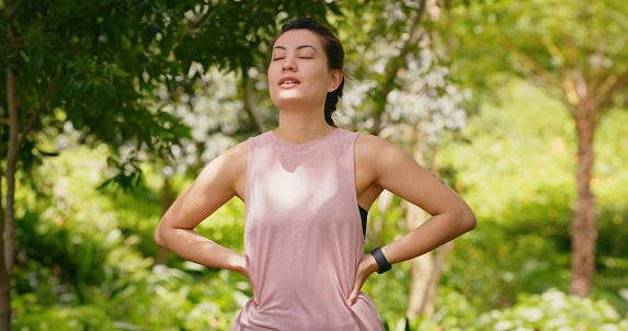 Calm runner woman doing meditation in park or nature environment, standing proud with success, mission and goal mindset. Athlete, fitness or sports person breathing fresh air before workout exercise