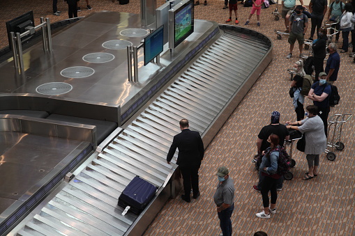 Image of the Baggage Claim area at Winnipeg International Airport, shot from above with people waiting for their luggage.