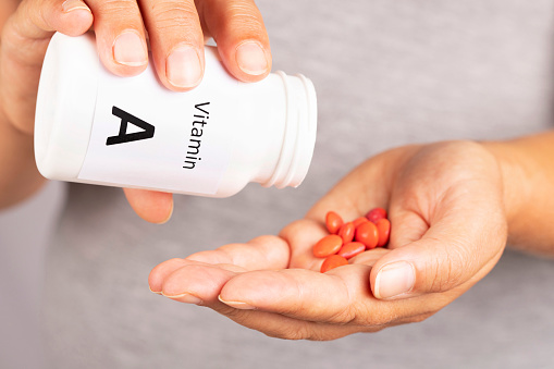 Woman hand takes vitamin A  from medicine container