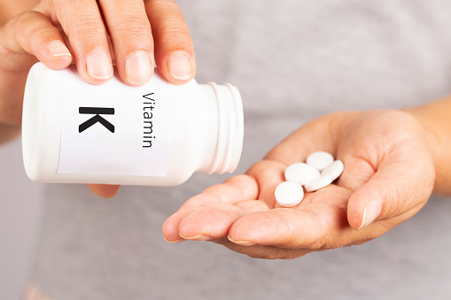 Woman hand takes vitamin K  from medicine container