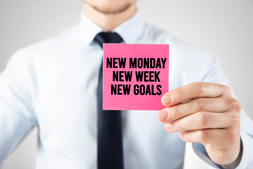 New monday new week new goals message on card holding by businessman
