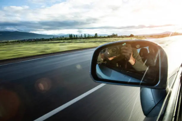 Photo of Reflection in car mirror of hands with camera.