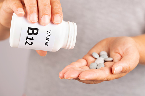 Woman hand takes vitamin B12  from medicine container