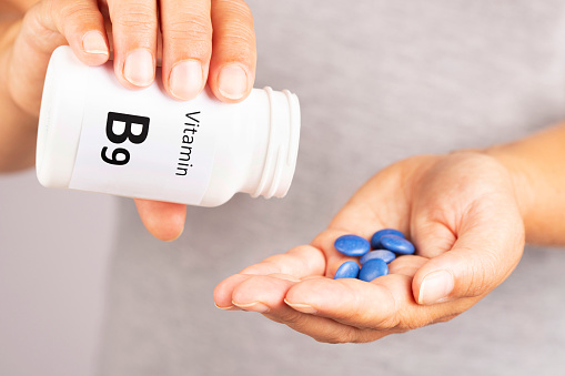 Woman hand takes vitamin B9  from medicine container