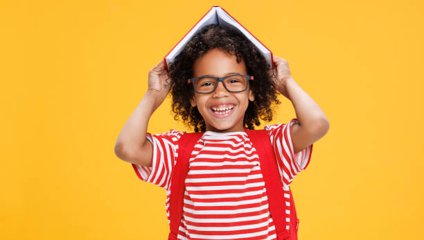 istock Happy ethnic schoolboy playing with book 1420804643
