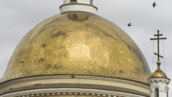 Birds flying near beautiful Church, religion concept. Orthodox golden crosses and domes on of the Church against the background of clouds.