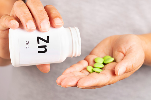 Woman hand takes Zinc  Mineral Supplement  from medicine container